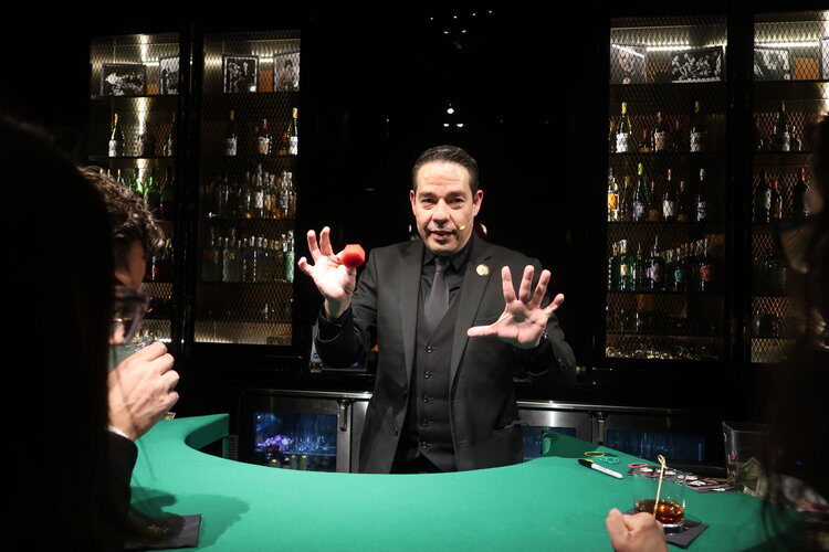 Trade show booth magician performing close-up sleight of hand to draw a crowd