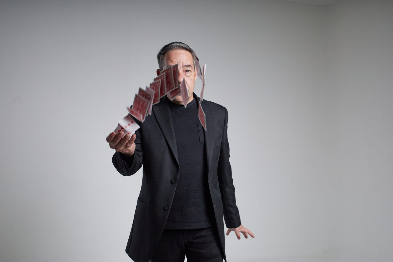 Gozner in a black suit fanning cards